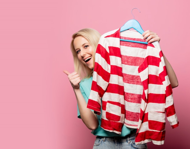 Belle femme avec chemise sur ahanger sur mur rose