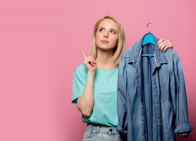 Belle femme avec une chemise sur un cintre sur mur rose