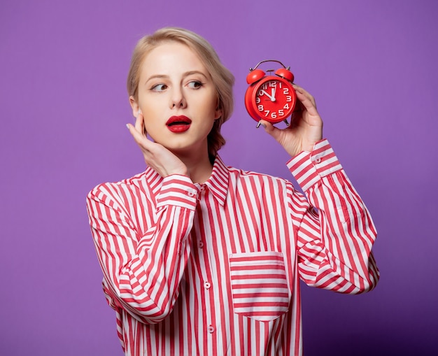 Belle femme en chemise rayée rouge avec réveil