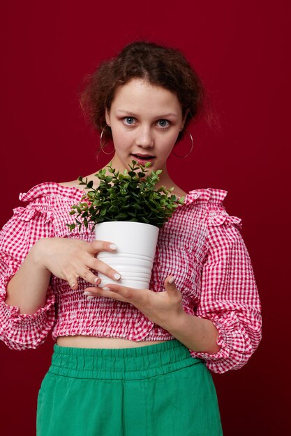 Belle femme en chemisier rose pose avec une plante en gros plan pot blanc