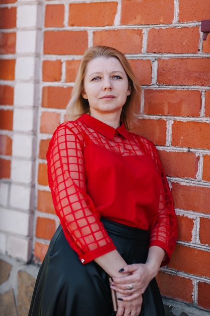 belle femme en chemisier rouge. rides sur le visage de la femme. blonde dans une blouse rouge. une belle maman