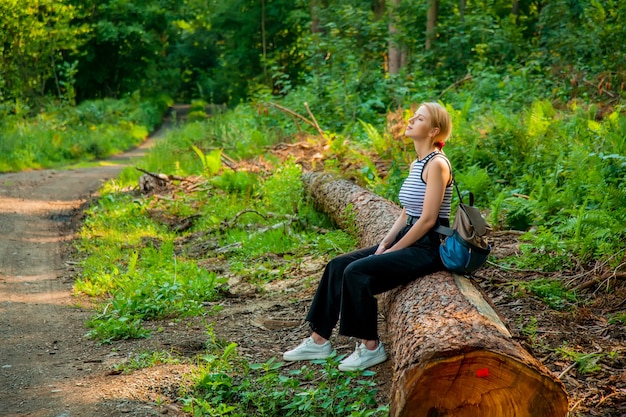 La belle femme de cheveux blonds s'assied sur la forêt de connexion