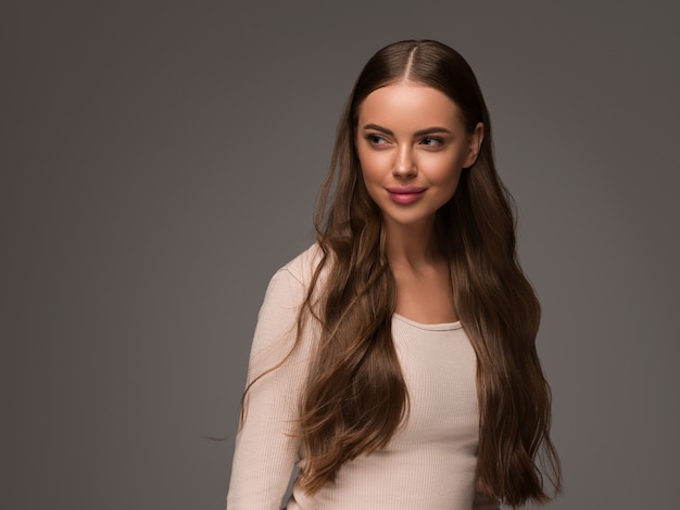 Belle femme avec des cheveux longs bouclés en bonne santé. Beauté des cheveux style décontracté naturel. Fond noir.