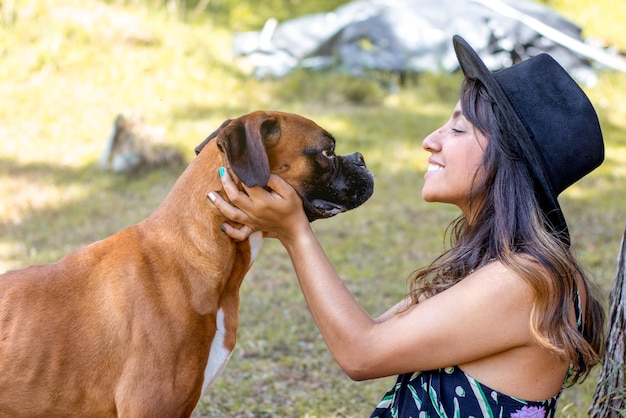 Belle femme et chien boxer mignon dans une journée ensoleillée à la campagne