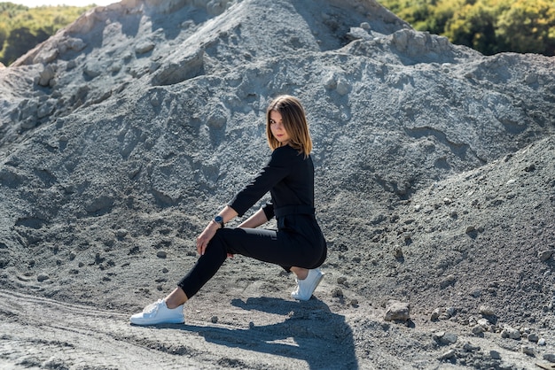 Belle femme en combinaison posant pour la caméra dans la carrière de sable