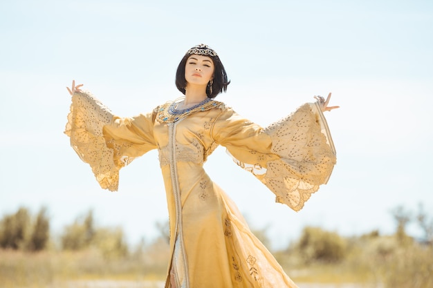 Belle femme comme la reine égyptienne Cléopâtre sur dans le désert en plein air