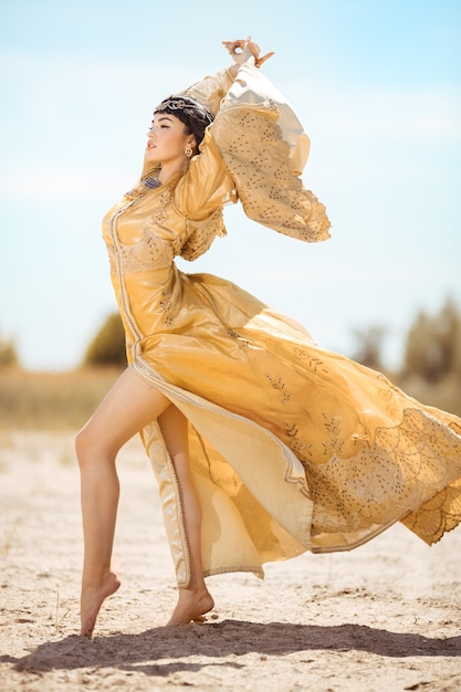 Belle femme comme la reine égyptienne Cléopâtre sur dans le désert en plein air