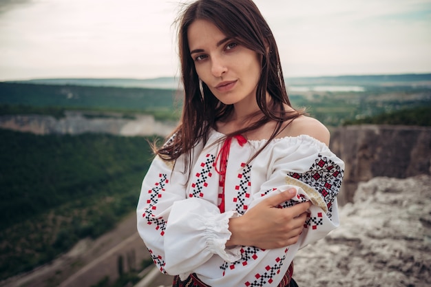 Belle femme en costume roumain traditionnel sur fond flou vert montagne