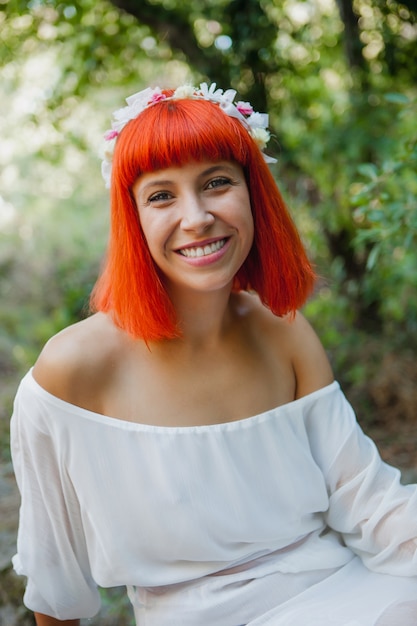 Belle femme avec une couronne de fleurs assis près d&#39;une cascade