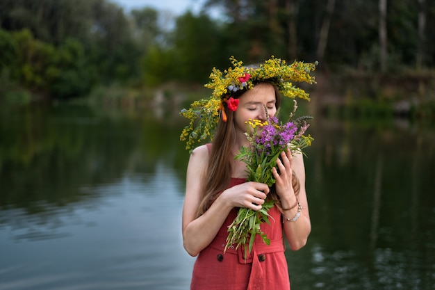 Belle femme avec une couronne sur la tête de fleurs sauvages sur fond de rivière. Vacances Ivan Kupala.