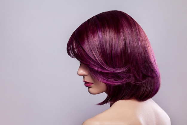 Belle femme avec une courte coiffure de couleur violette montrant sa couleur de cheveux élégante et brillante