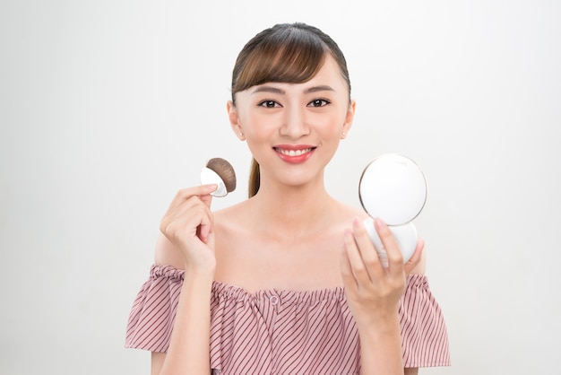 Belle femme avec coussin feuilletée et miroir appliquant le fond de teint en poudre de maquillage