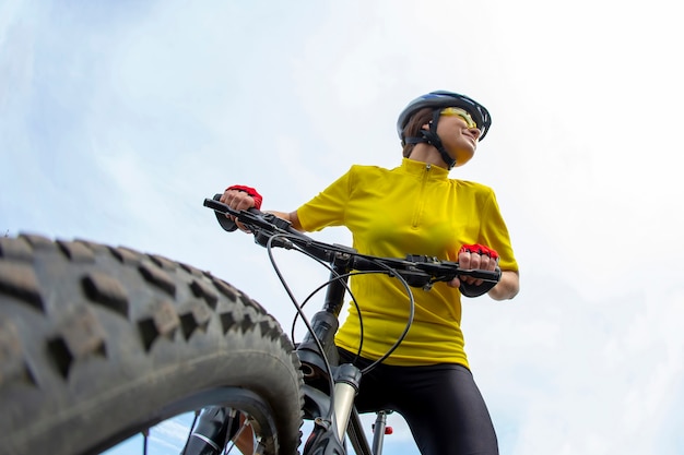 Belle femme cycliste en jaune avec impatience, tenant le vélo