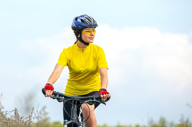 Belle femme cycliste en vêtements jaunes sur le vélo sports loisirs et divertissement pour la santé