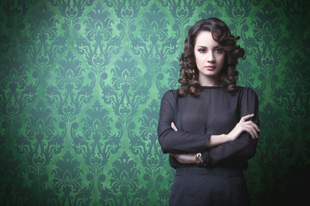 Belle femme dans une chambre vintage verte. Maquillage et coiffure professionnels. Intérieur rétro riche. Image tonique