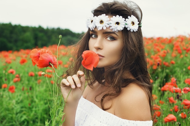 Belle femme dans un champ avec beaucoup de fleurs de pavot