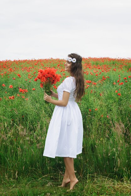Belle femme dans un champ avec beaucoup de fleurs de pavot