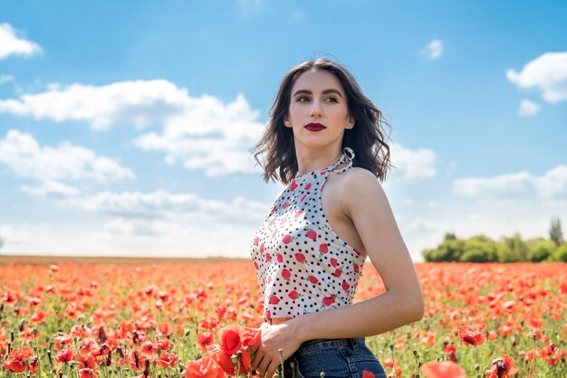 Belle femme dans un champ de pavot, profitez de l'heure d'été