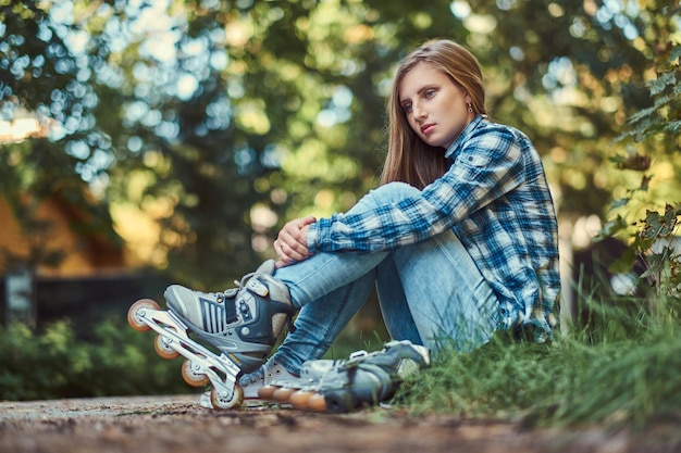 Une belle femme dans une chemise polaire et un jean se reposant après le patinage à roulettes.