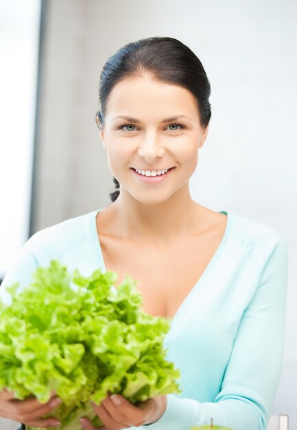 belle femme dans la cuisine avec des feuilles de salade verte..