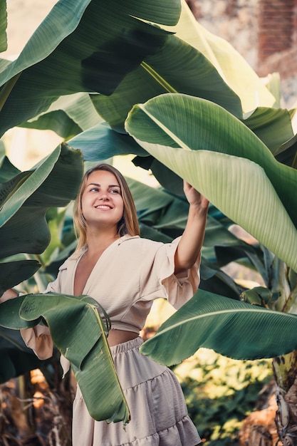 Belle femme dans la jungle Un complexe ou un hôtel avec des arbres et des plantes tropicales Femme avec près de feuille de bananier Fille en vacances dans la forêt tropicale