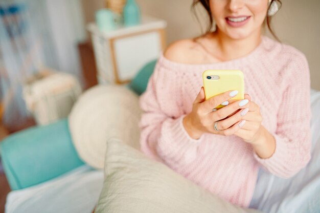 Belle femme dans une maison confortable regarde le téléphone