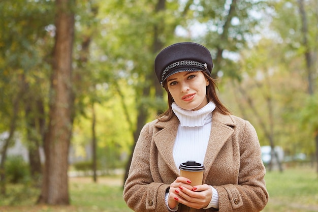 Belle femme dans le parc d'automne avec du café