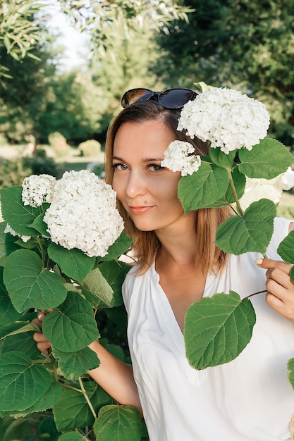 Photo une belle femme dans un parc d'été. portrait d'une femme avec des fleurs.