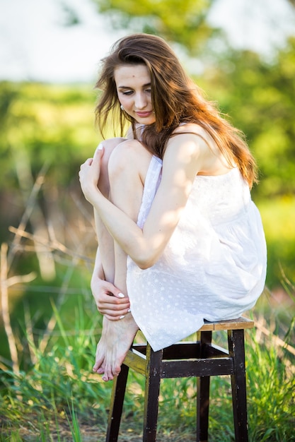 Belle femme dans une robe blanche sur une chaise