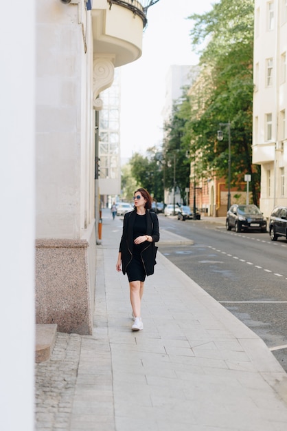 Belle femme dans une robe noire sur fond d'un paysage urbain