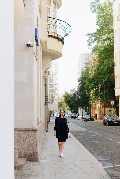 Belle femme dans une robe noire sur fond d'un paysage urbain