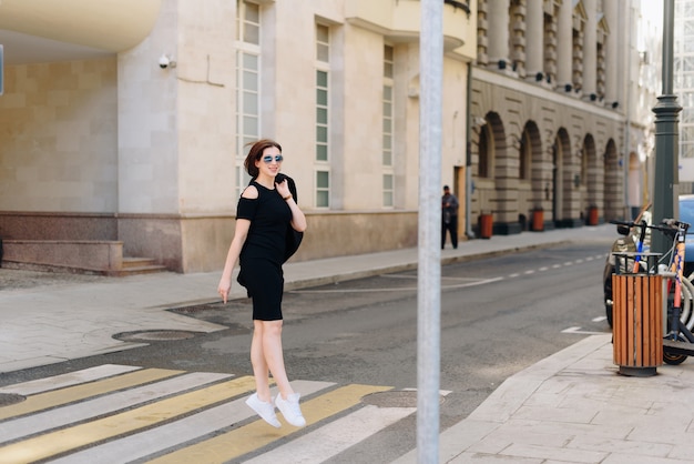 Belle femme dans une robe noire sur fond d'un paysage urbain