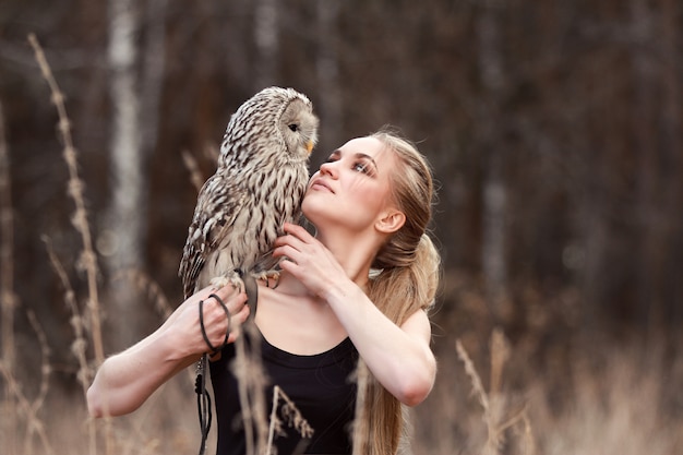 Belle femme dans une robe noire avec un hibou sur son bras.