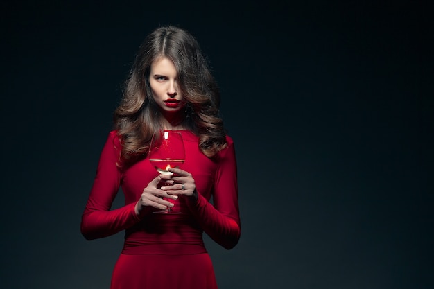 Belle femme dans une robe rouge avec un verre de vin