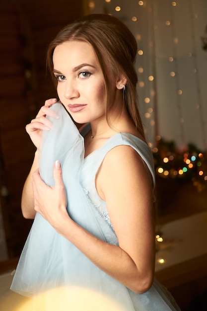 belle femme dans une robe de soirée bleue sur fond sombre avec des guirlandes