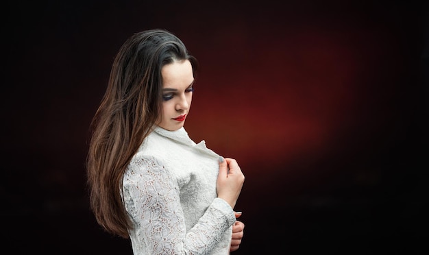 Belle femme dans un studio sombre dans une chemise blanche se présentant à la caméra