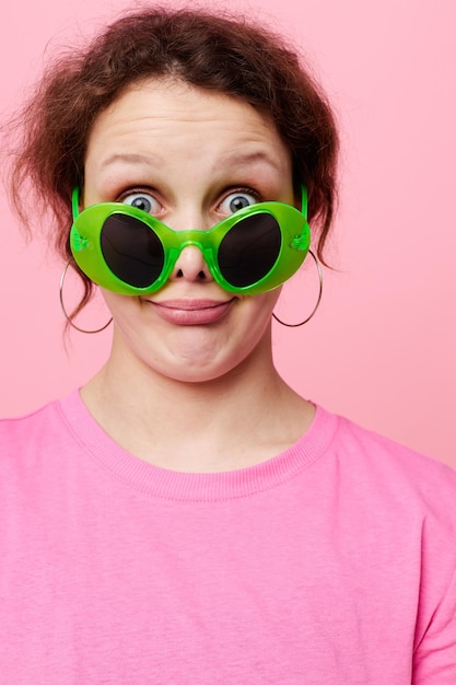 Photo belle femme dans un t-shirt rose lunettes vertes mode jeunesse fond de couleur rose inchangé. photo de haute qualité