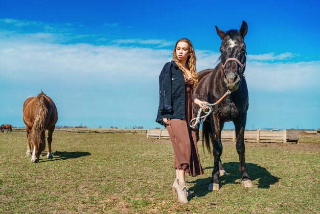 Belle femme debout dans un champ avec un cheval