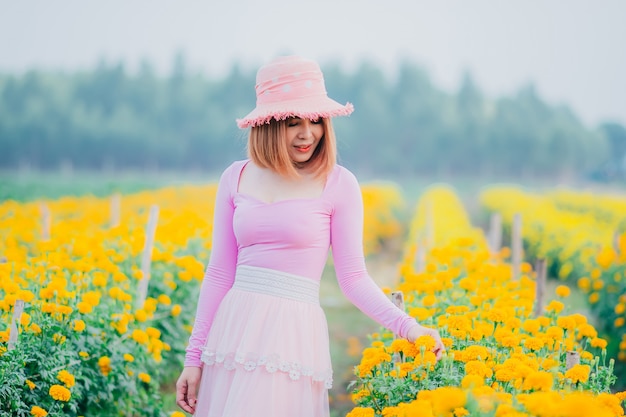 Belle femme debout dans le jardin de souci. Femme qui marche dans le jardin fleuri.