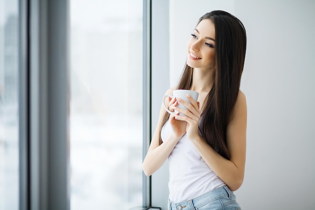 Belle femme debout près des fenêtres. Belle matinée