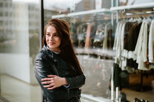 Belle femme debout si devant le magasin de la fenêtre.