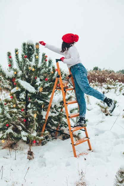 Belle femme décorant le sapin de Noël à l'extérieur