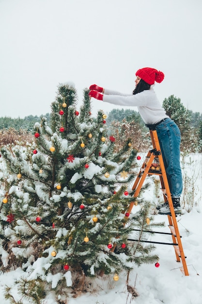 Belle femme décorant le sapin de Noël à l'extérieur