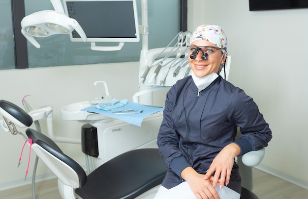 Belle femme dentiste assise près du fauteuil dentaire