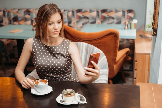 Belle femme détendue à l'aide d'un téléphone portable dans un café faisant selfie