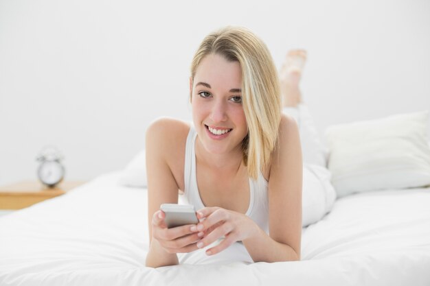 Belle femme détendue tenant son smartphone, souriant à la caméra