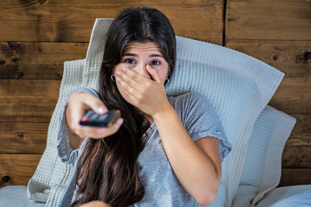 Belle femme devant la télé et allongée sur le lit.