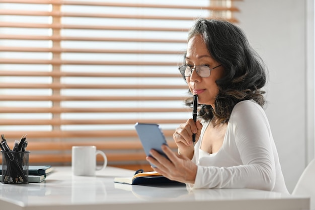 Belle femme discutant sur un réseau social ou faisant des achats en ligne sur un smartphone Concept de technologie de retraite