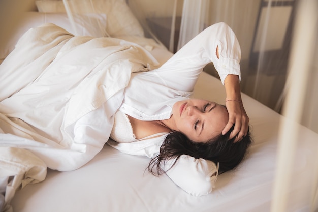 Belle femme dormant dans un lit blanc le matin.