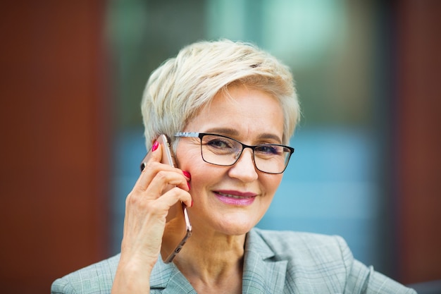 belle femme élégante avec une coupe courte dans un costume appelle au téléphone